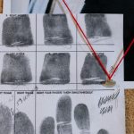 Detailed close-up of fingerprint card pinned on a corkboard, showcasing identity documentation.