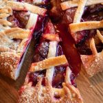 Close-up of a homemade cherry pie with a slice removed, revealing juicy filling.